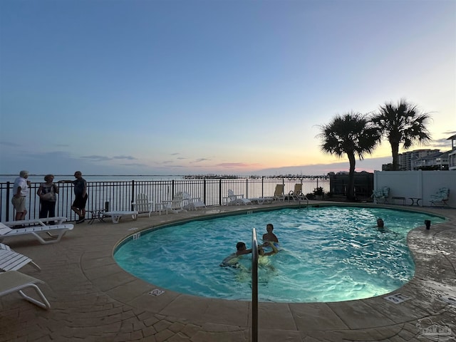 pool at dusk featuring a patio area