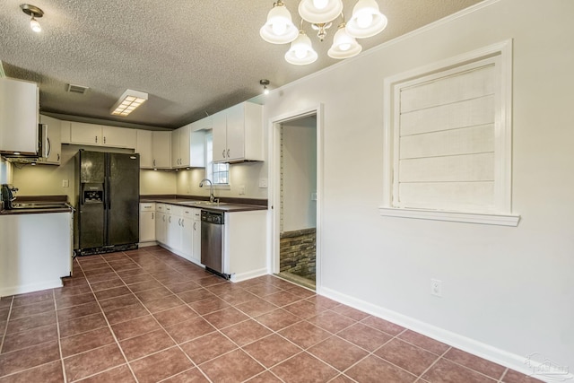 kitchen with sink, white cabinets, dark tile patterned floors, stainless steel appliances, and a textured ceiling