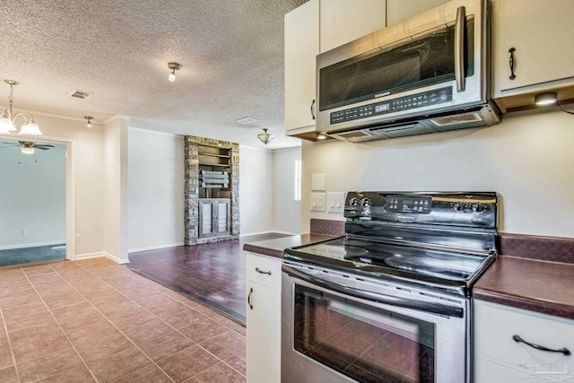 kitchen with a textured ceiling, pendant lighting, ceiling fan, stainless steel appliances, and white cabinets