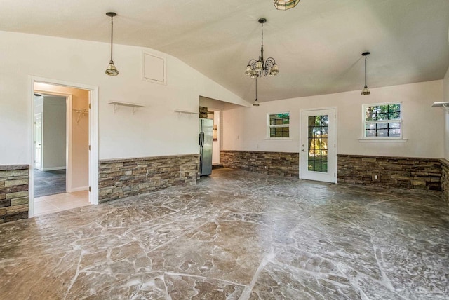 unfurnished living room with lofted ceiling and a chandelier