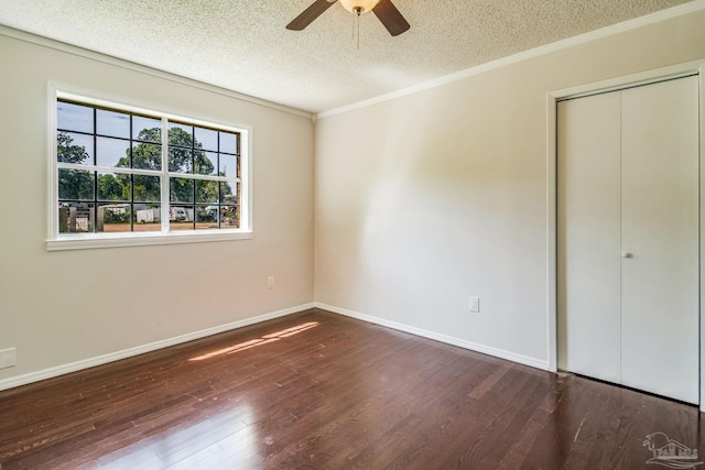 unfurnished bedroom featuring dark wood-type flooring, ceiling fan, ornamental molding, a textured ceiling, and a closet