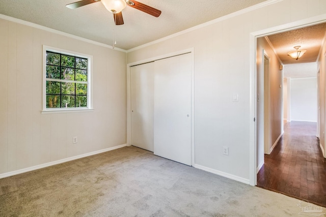 unfurnished bedroom featuring crown molding, a closet, light colored carpet, and a textured ceiling