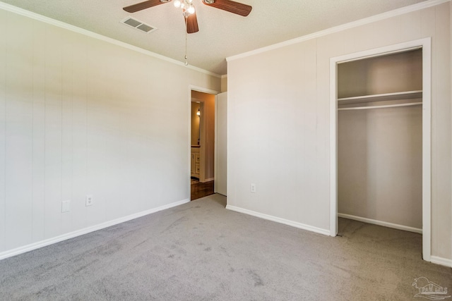 unfurnished bedroom featuring crown molding, a closet, ceiling fan, and carpet flooring