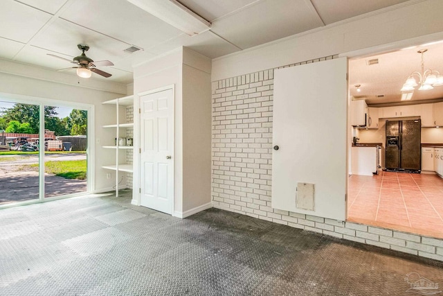 spare room with ceiling fan with notable chandelier, brick wall, and carpet floors