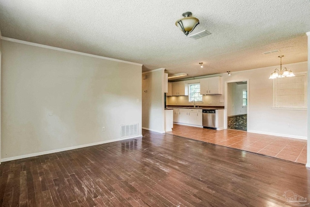 unfurnished living room with an inviting chandelier, sink, ornamental molding, dark wood-type flooring, and a textured ceiling