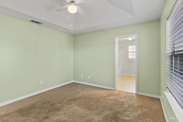 carpeted empty room featuring ceiling fan and a tray ceiling