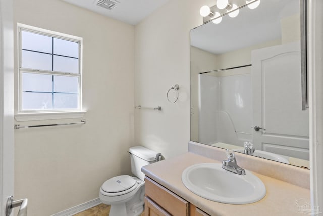 bathroom featuring toilet, vanity, and a shower