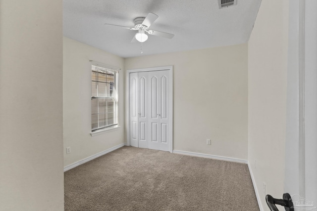 unfurnished bedroom featuring carpet, a closet, ceiling fan, and a textured ceiling