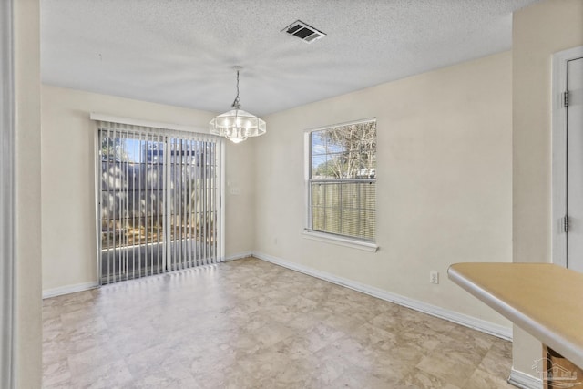 unfurnished dining area featuring a notable chandelier and a textured ceiling