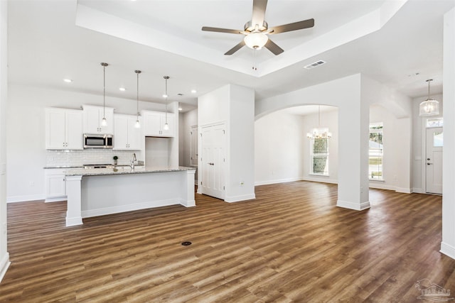 6575 Gentle Rain Dr, Milton, FL 32570 - kitchen with stainless steel microwave, arched walkways, a raised ceiling, open floor plan, and white cabinets