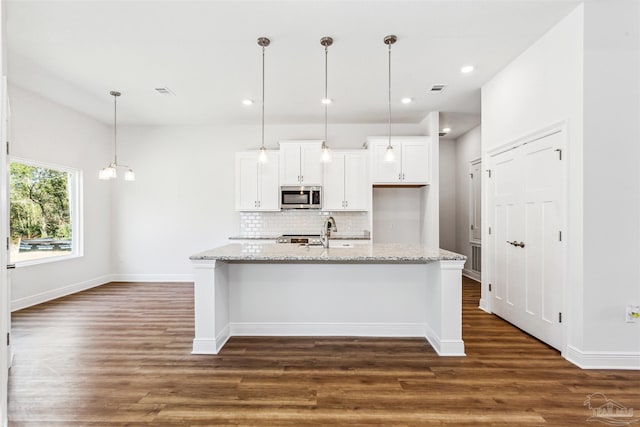 6575 Gentle Rain Dr, Milton, FL 32570 - kitchen with stainless steel microwave, decorative backsplash, white cabinetry, dark wood-type flooring, and baseboards
