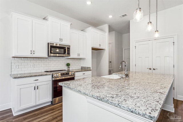 6575 Gentle Rain Dr, Milton, FL 32570 - kitchen featuring appliances with stainless steel finishes, dark wood-type flooring, a center island with sink, white cabinets, and recessed lighting