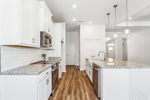 6575 Gentle Rain Dr, Milton, FL 32570 - kitchen with stainless steel appliances, arched walkways, light wood finished floors, white cabinetry, and tasteful backsplash