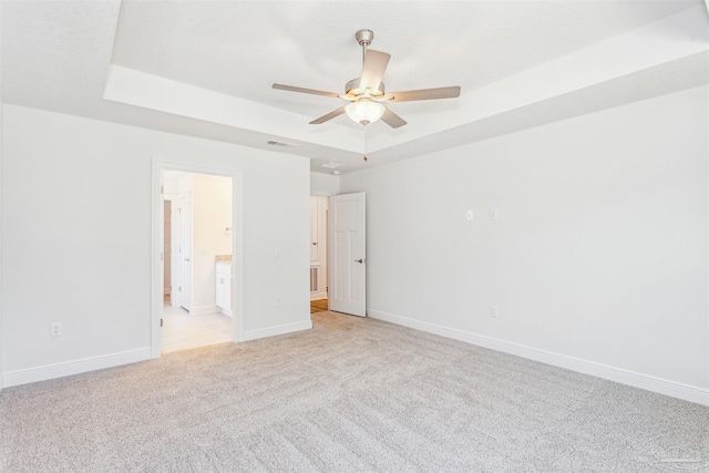 6575 Gentle Rain Dr, Milton, FL 32570 - unfurnished bedroom featuring light colored carpet, baseboards, ensuite bathroom, a tray ceiling, and a ceiling fan