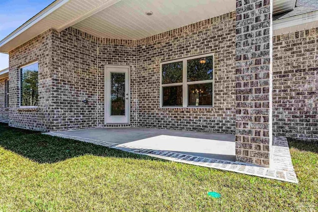6575 Gentle Rain Dr, Milton, FL 32570 - view of exterior entry with brick siding, a patio, and a yard