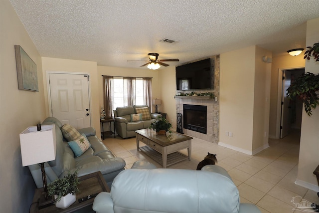 tiled living room featuring ceiling fan, a fireplace, and a textured ceiling