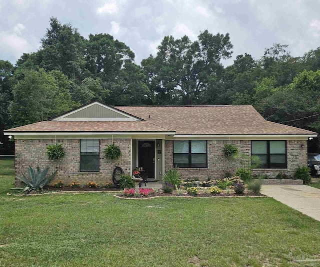 ranch-style house with a front lawn, roof with shingles, and brick siding