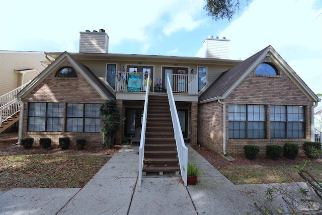 view of front of house featuring stairway, brick siding, and a chimney