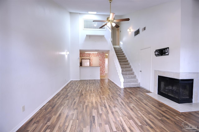 unfurnished living room featuring visible vents, stairway, a multi sided fireplace, ceiling fan, and baseboards