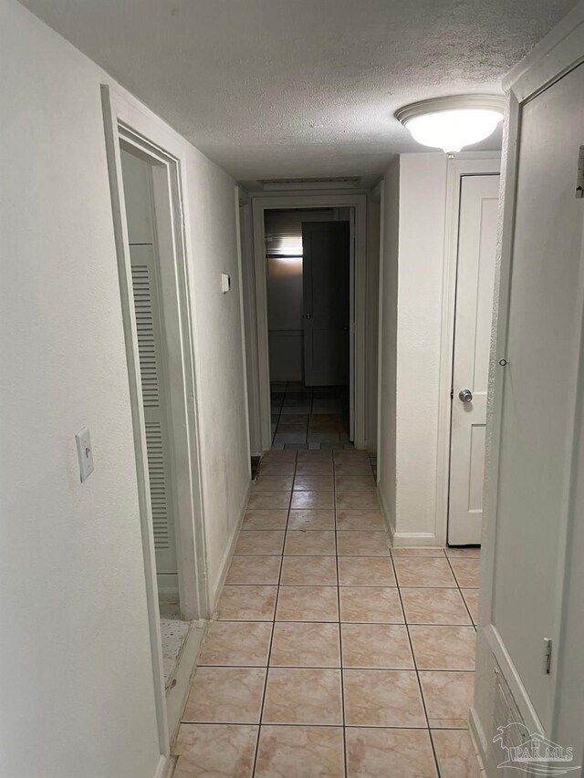 hallway featuring a textured ceiling and light tile patterned floors