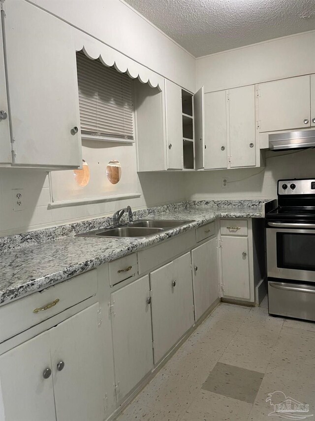 kitchen featuring white cabinets, electric range, sink, and a textured ceiling