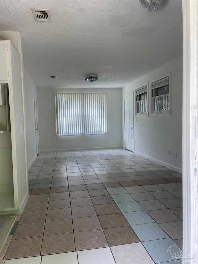 empty room with a textured ceiling and tile patterned floors