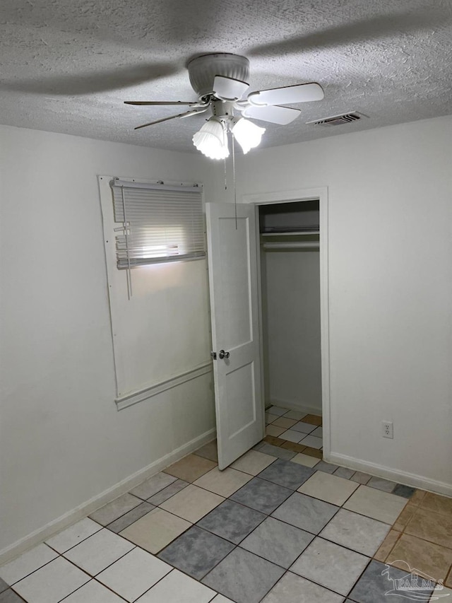 unfurnished bedroom featuring a closet, ceiling fan, a textured ceiling, and light tile patterned flooring