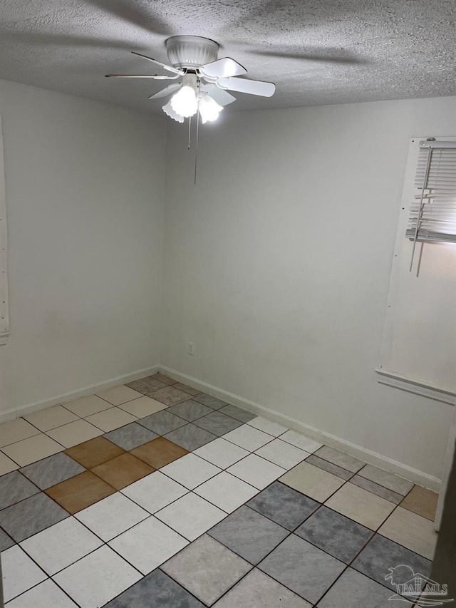 spare room with a textured ceiling, ceiling fan, and light tile patterned flooring