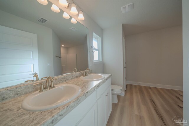 bathroom with hardwood / wood-style flooring, vanity, toilet, and a shower