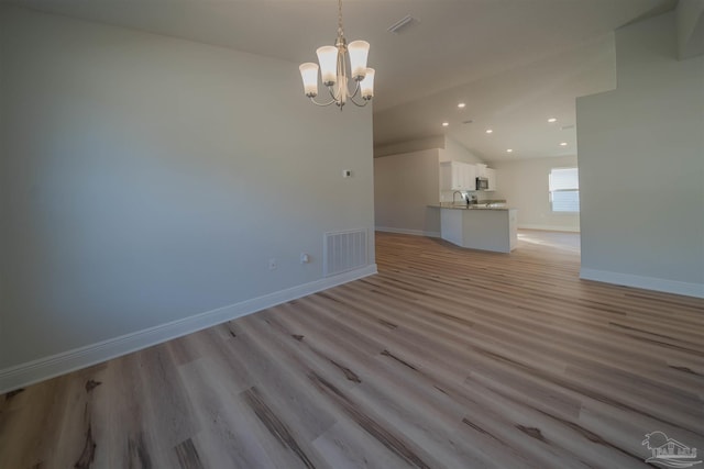 interior space with lofted ceiling, sink, a chandelier, and light wood-type flooring