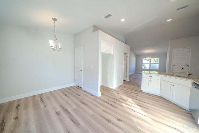 kitchen with dishwasher, sink, white cabinets, a notable chandelier, and light stone countertops