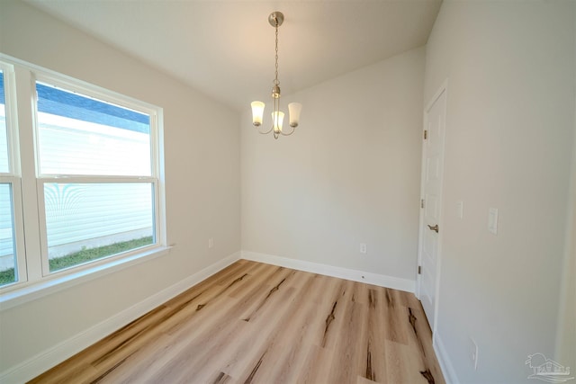 unfurnished room featuring light hardwood / wood-style flooring, a chandelier, and plenty of natural light