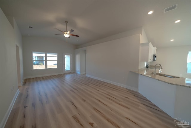 unfurnished living room with lofted ceiling, sink, light hardwood / wood-style flooring, and ceiling fan