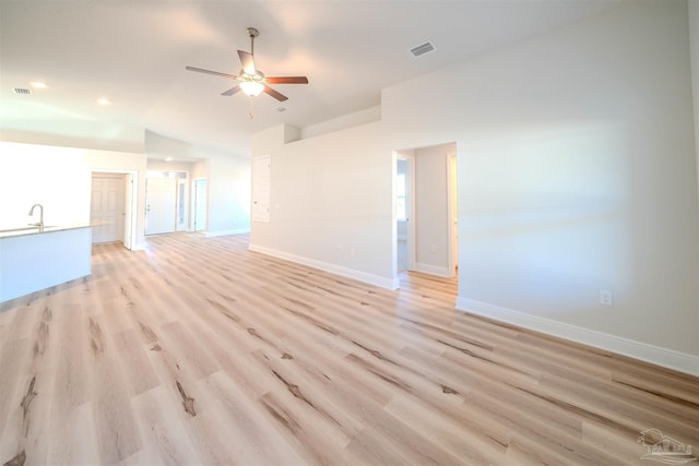 unfurnished living room with light hardwood / wood-style flooring, ceiling fan, and vaulted ceiling