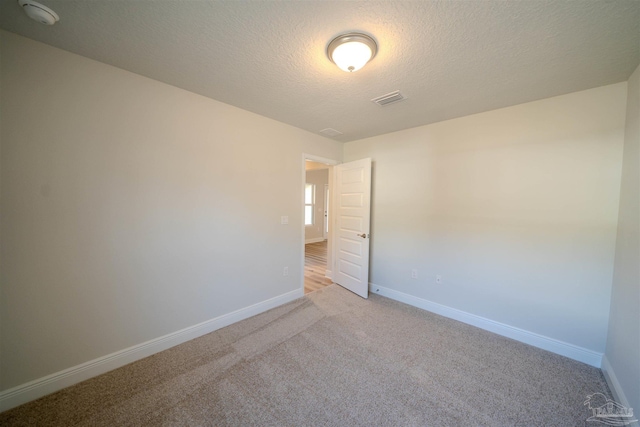 empty room with carpet floors and a textured ceiling