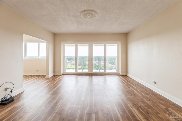 unfurnished room with a textured ceiling and wood-type flooring