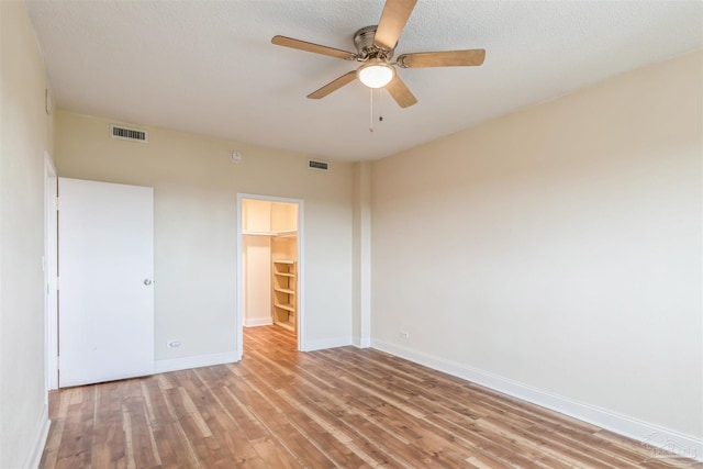 empty room featuring ceiling fan, light hardwood / wood-style floors, and a textured ceiling