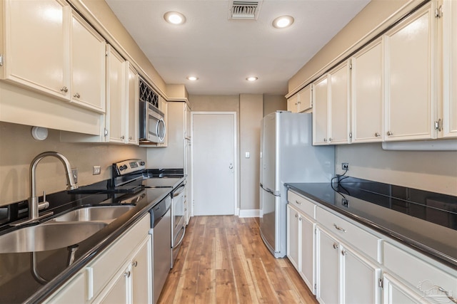 kitchen featuring appliances with stainless steel finishes, light hardwood / wood-style flooring, white cabinets, and sink