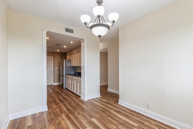 unfurnished living room with a notable chandelier and hardwood / wood-style flooring