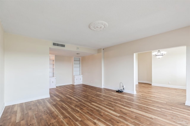 spare room with wood-type flooring, a textured ceiling, and a chandelier