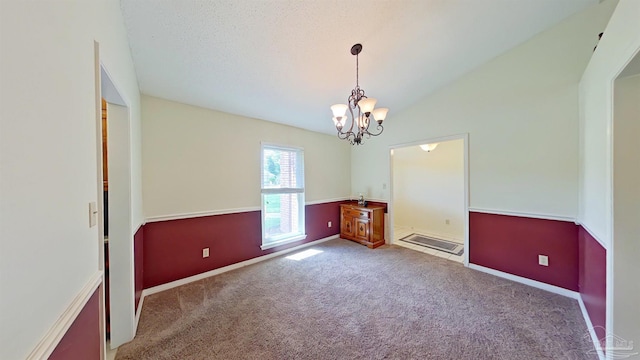 carpeted spare room with lofted ceiling, a textured ceiling, and a chandelier