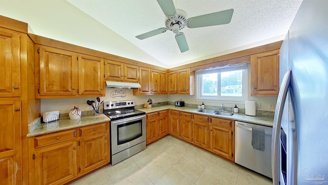 kitchen featuring light tile patterned flooring, lofted ceiling, sink, stainless steel appliances, and a textured ceiling