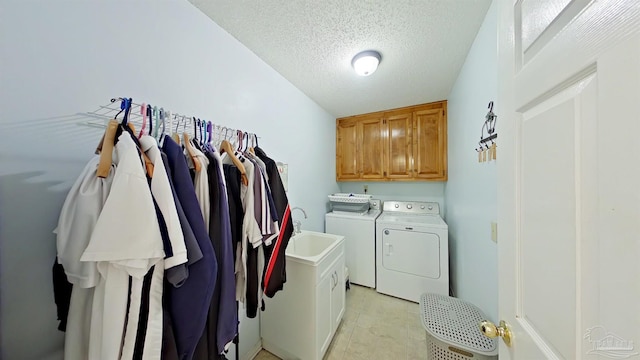 washroom featuring cabinets, sink, washer and dryer, and a textured ceiling