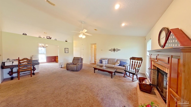 carpeted living room featuring lofted ceiling, a brick fireplace, and ceiling fan with notable chandelier