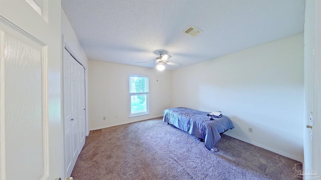 carpeted bedroom featuring ceiling fan and a textured ceiling