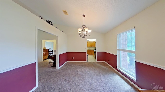 carpeted empty room with vaulted ceiling, a textured ceiling, and a notable chandelier