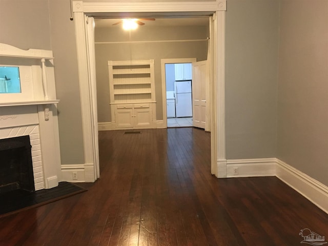 interior space with a brick fireplace and dark wood-type flooring