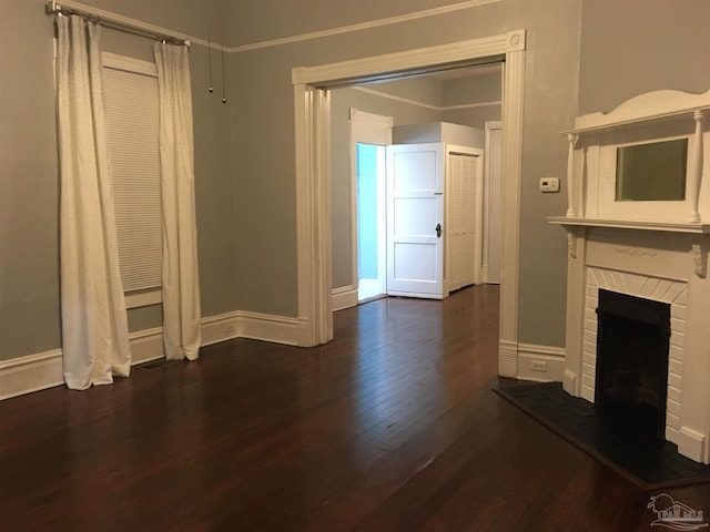 unfurnished living room featuring a brick fireplace and dark hardwood / wood-style flooring