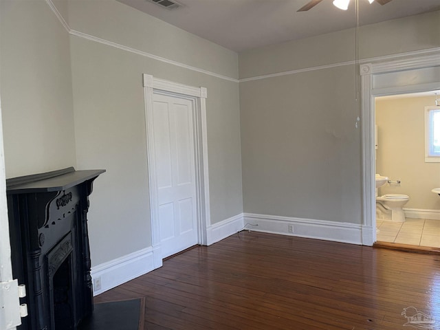 unfurnished bedroom with dark wood-type flooring, ceiling fan, a closet, and ensuite bath