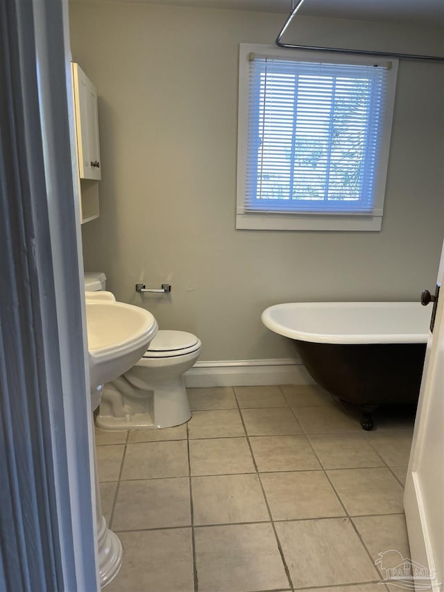 bathroom featuring toilet, tile patterned floors, and a bath